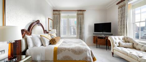 A hotel room with a large bed, a TV, a desk, and a chair.