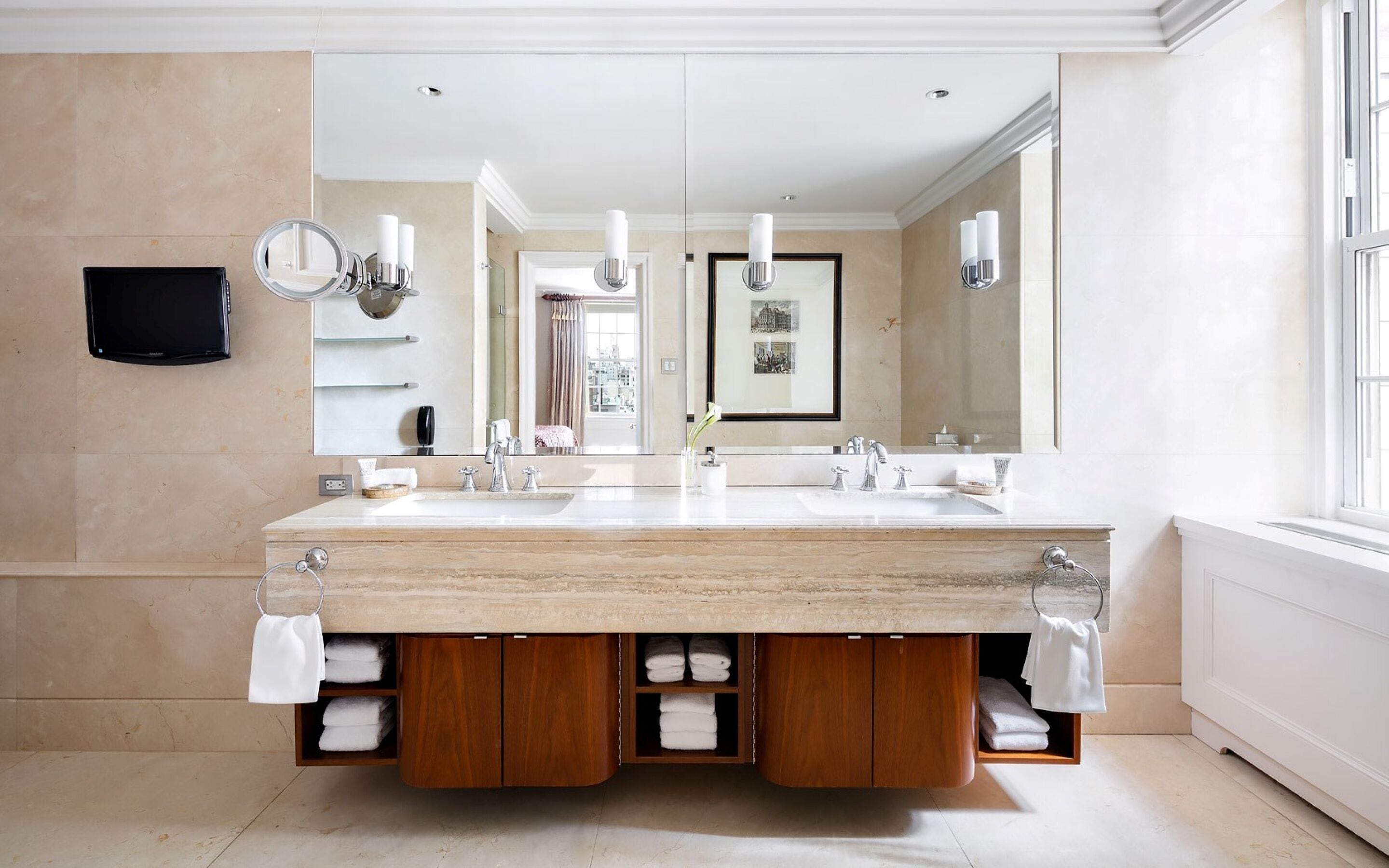 A modern bathroom with a large vanity, two sinks, a large mirror, and a framed picture on the wall.