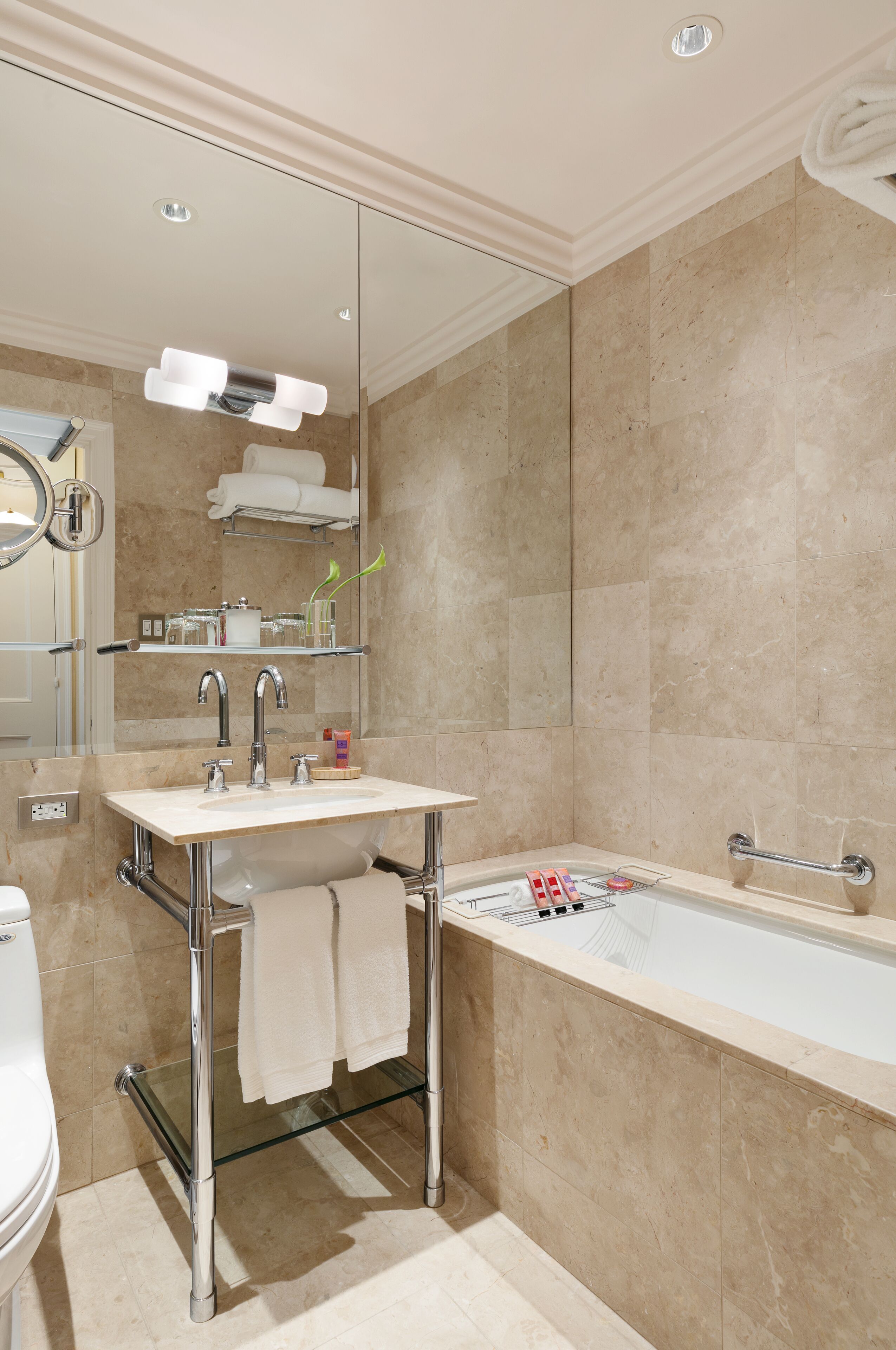 A modern bathroom with a glass-enclosed sink, a bathtub, and a mirror above the sink.