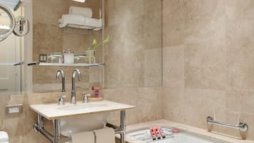 A modern bathroom with a glass-enclosed sink, a bathtub, and a mirror above the sink.