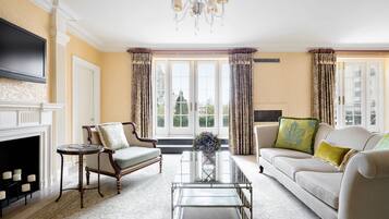 A living room with a fireplace, two armchairs, a sofa, a coffee table, and a TV mounted on the wall.