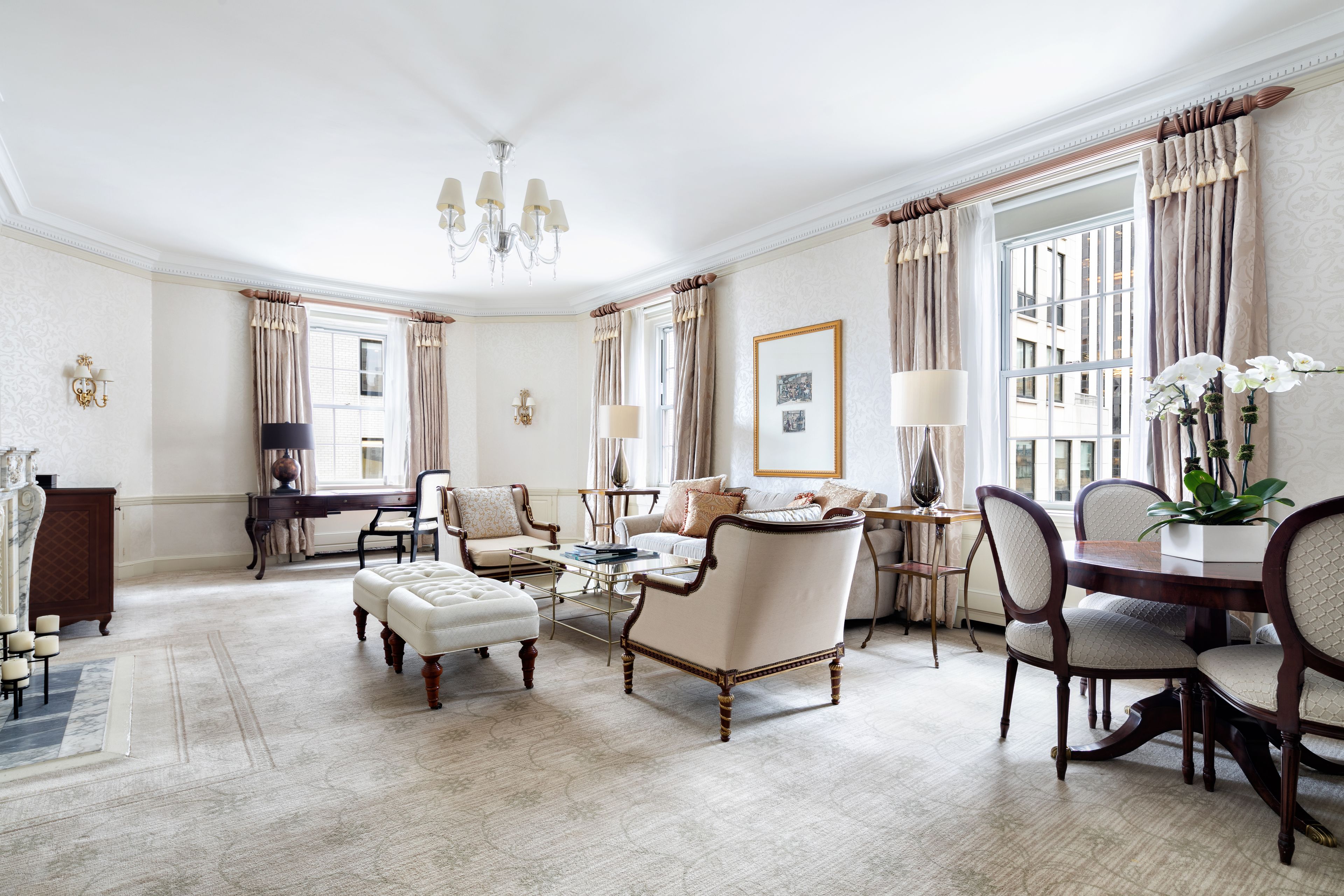 A spacious living room with a large window, elegant furniture, and a chandelier.