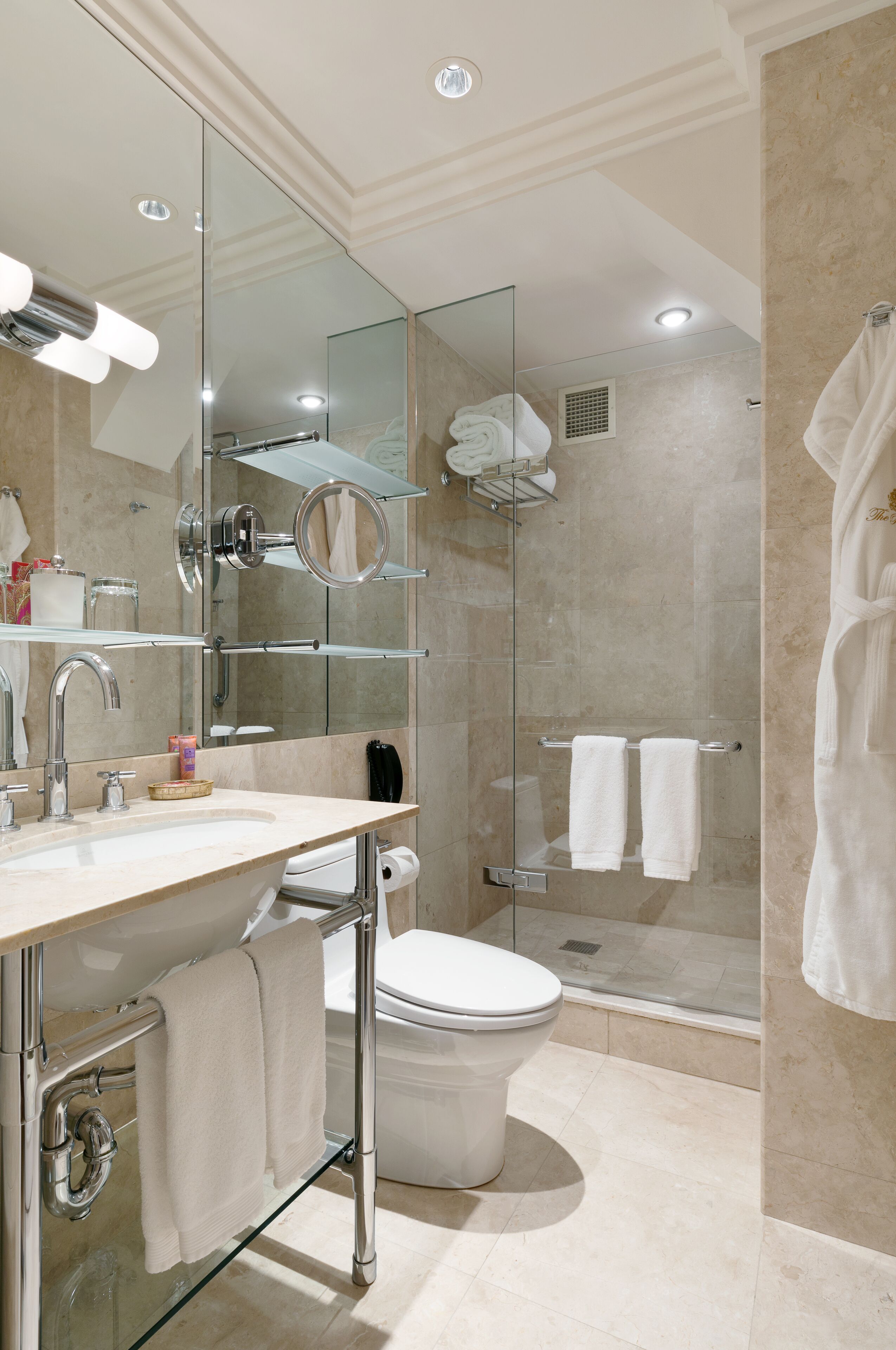 A modern bathroom with a glass-enclosed shower, a large mirror, and a vanity with a sink and towel rack.