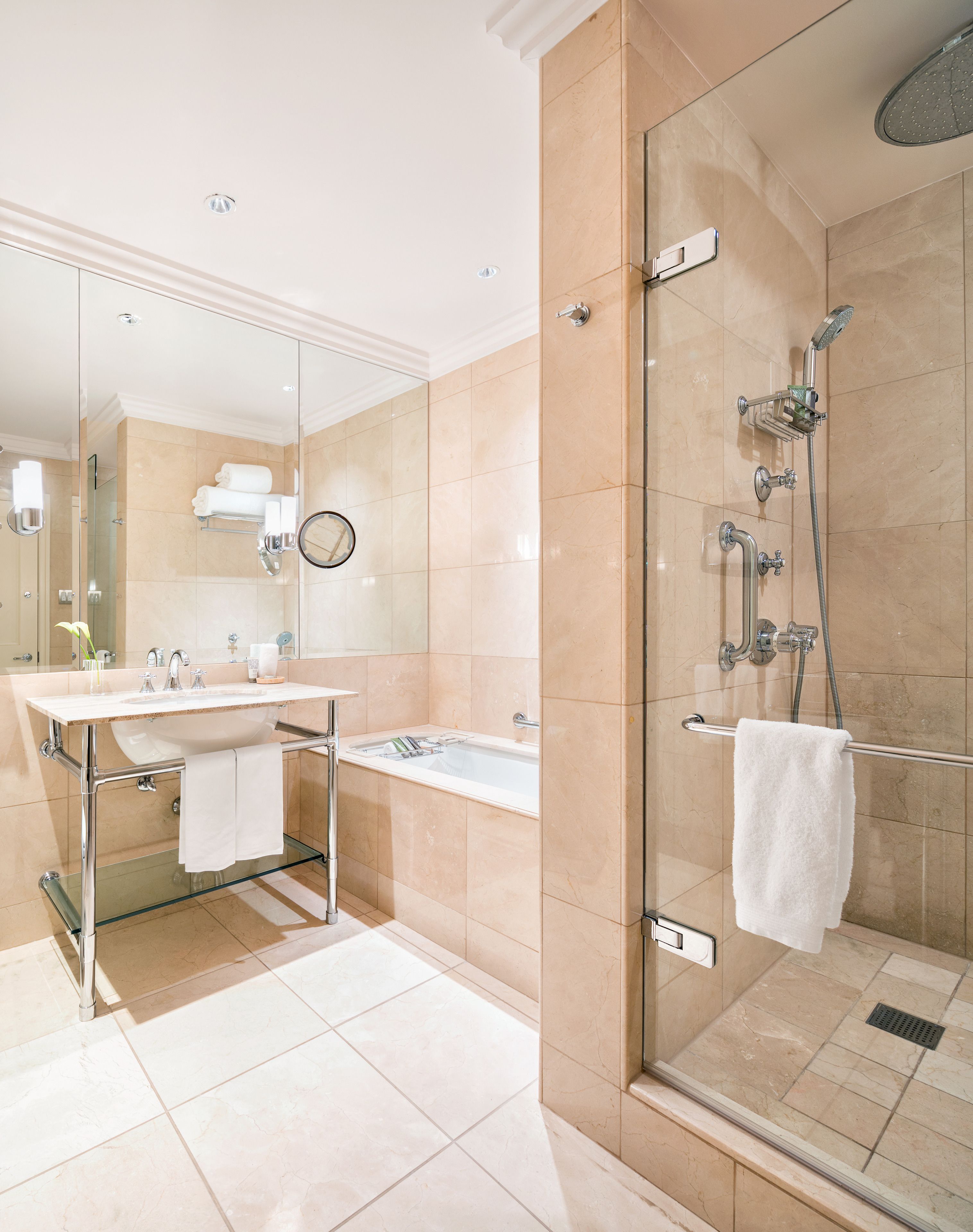 A modern bathroom with a glass-enclosed shower, a sink with a mirror, and a glass-topped vanity.
