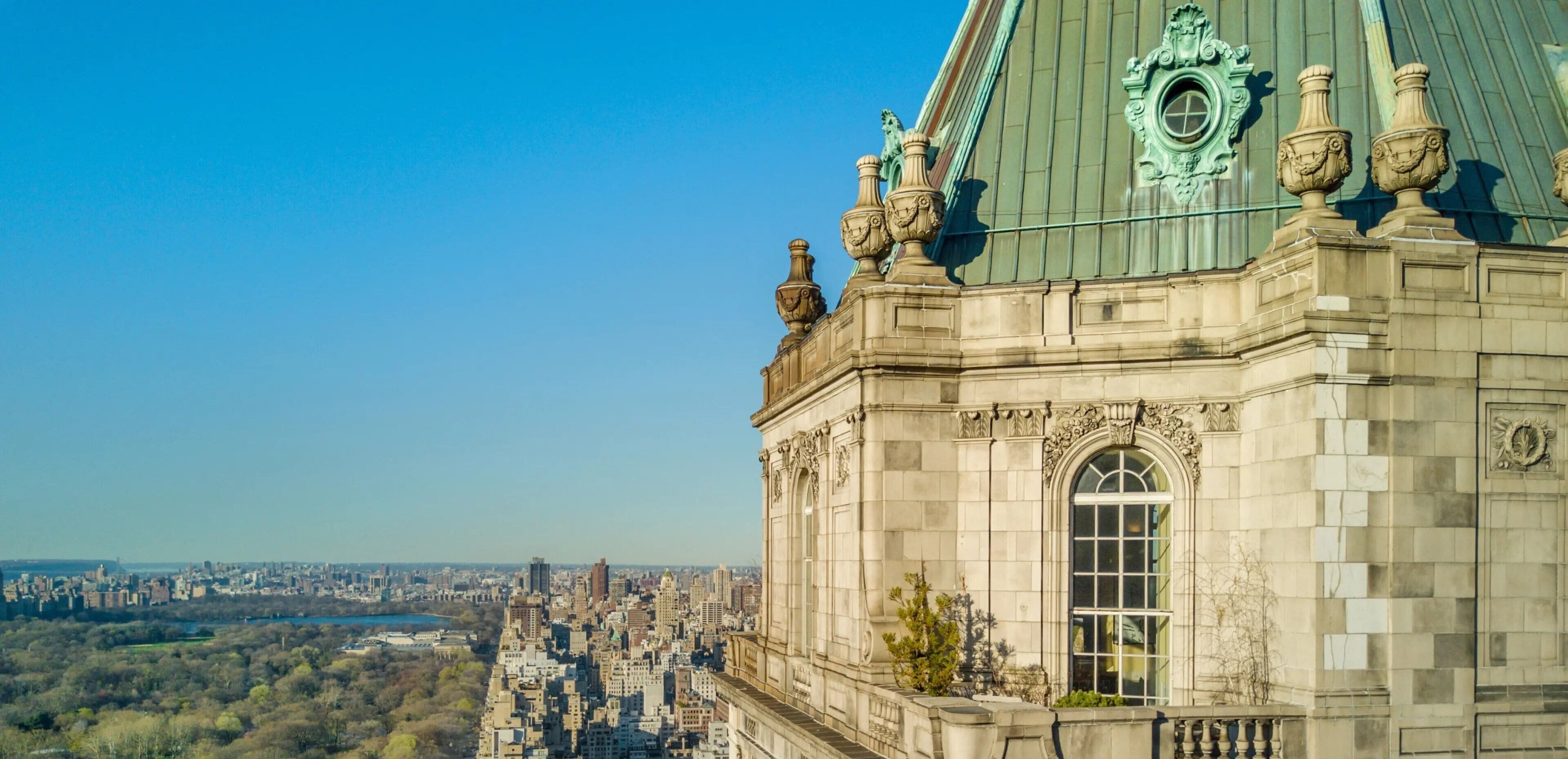 A historic building with ornate architectural details, a large arched window, and a view of a cityscape.