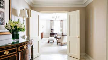 A hallway with a glass-top console table, a vase of flowers, and a door leading to another room.