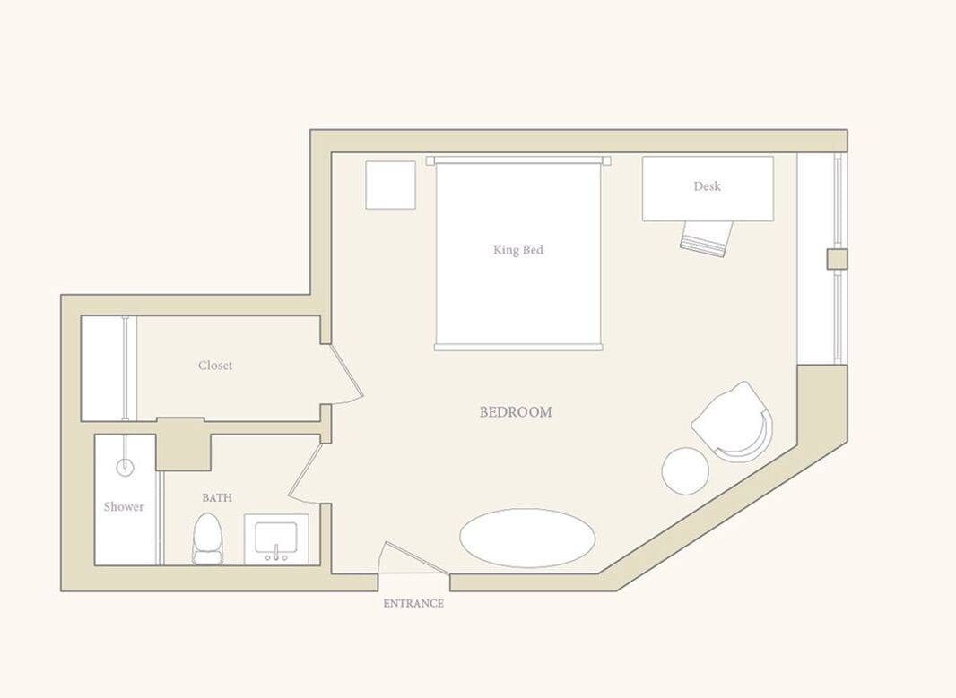 A bedroom with a king bed, a desk, a closet, a bathroom with a shower and toilet, and an entrance.