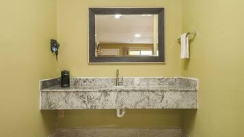 A bathroom with a granite countertop sink, a mirror, a towel rack, and a wall-mounted phone.