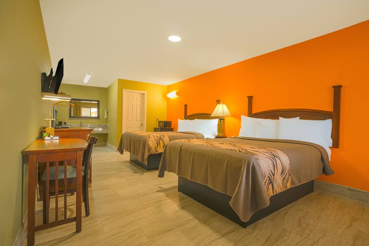 A hotel room with two beds, a desk, and a chair.
