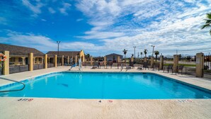 A swimming pool with lounge chairs and a lifeguard stand. - Aransas Bay Inn & Suites Corpus Christi by OYO (Aransas Pass)
