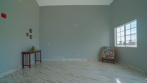A spacious room with a marble floor, a small wooden table with a plant, and a window with a city view. - Aransas Bay Inn & Suites Corpus Christi by OYO (Aransas Pass)