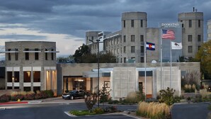 A hotel with a modern architectural design, featuring a prominent entrance with a flag display and a parking area. - DoubleTree by Hilton Denver - Thornton (Thornton)