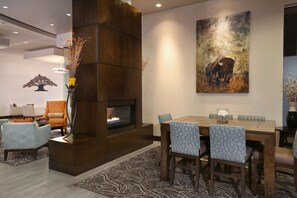 Cozy gathering space with a central fireplace, dining table, and artwork.
