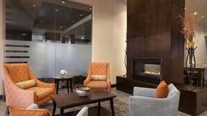 A modern living room with a fireplace, two armchairs, a sofa, and a coffee table. - DoubleTree by Hilton Denver - Thornton (Thornton)