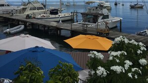 A marina with several boats docked, a wooden pier, and a yellow umbrella.