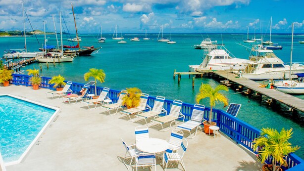A marina with boats docked, a swimming pool, and lounge chairs.