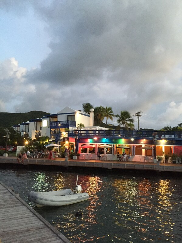 A waterfront restaurant with outdoor seating, a dock, and a boat.