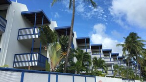A hotel with multiple balconies, palm trees, and a clear blue sky.