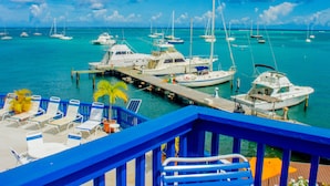 A marina with several boats docked, a pier with lounge chairs, and a clear blue sky.