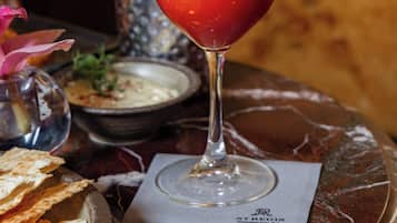 Un vaso de bebida roja con una decoración de camarones sobre una mesa de mármol.