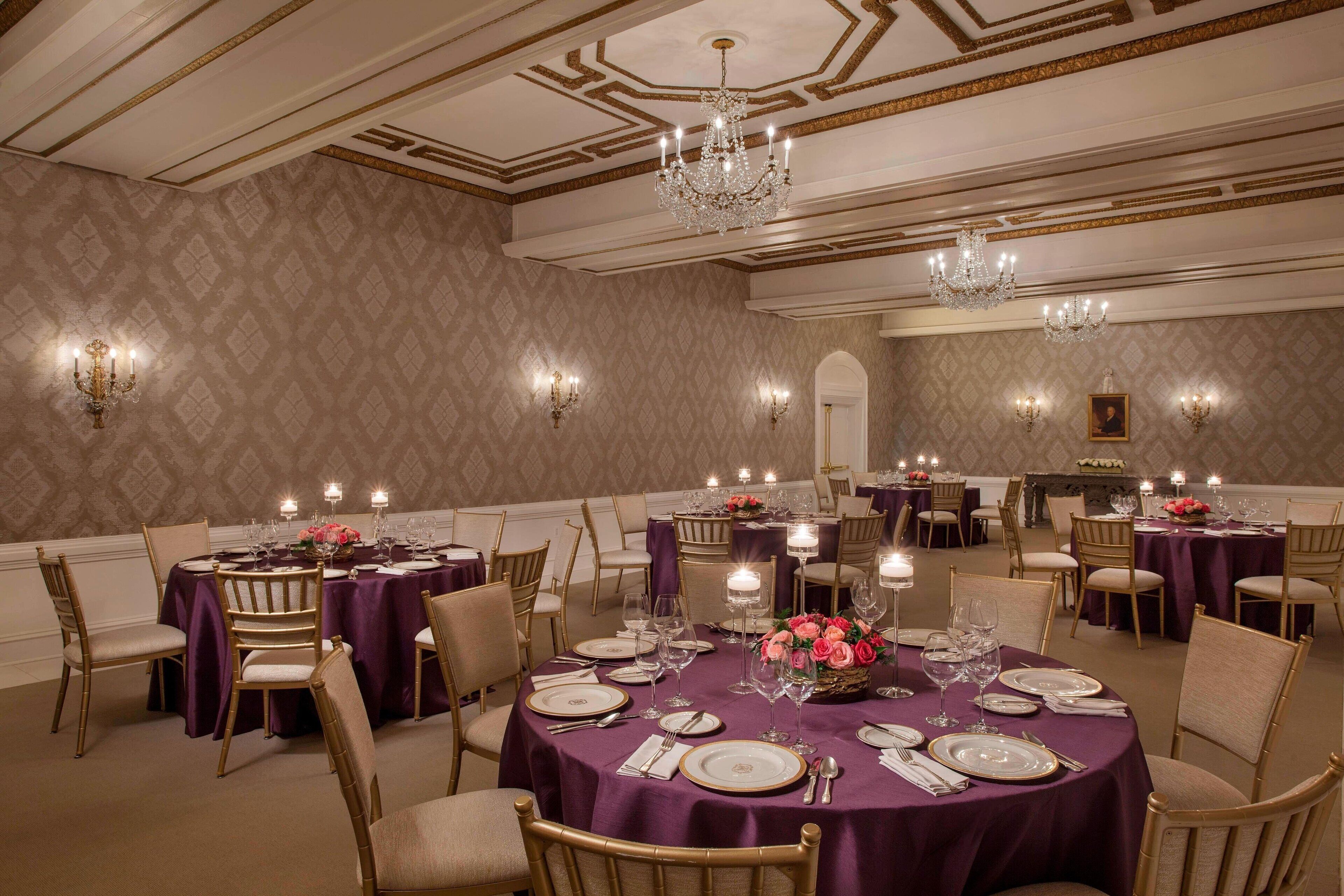 Un comedor elegante con mesas redondas, sillas doradas y candelabros.