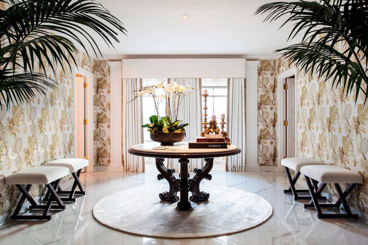 A round table with a vase of white orchids, a book titled "Windows," and a decorative item on the table.