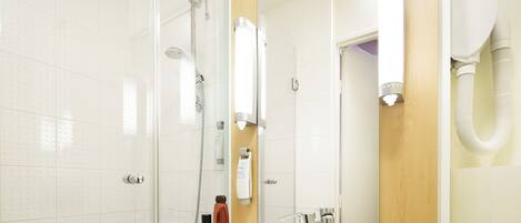 Un baño con cabina de ducha de vidrio, un lavabo con espejo y un dispensador de toallas.