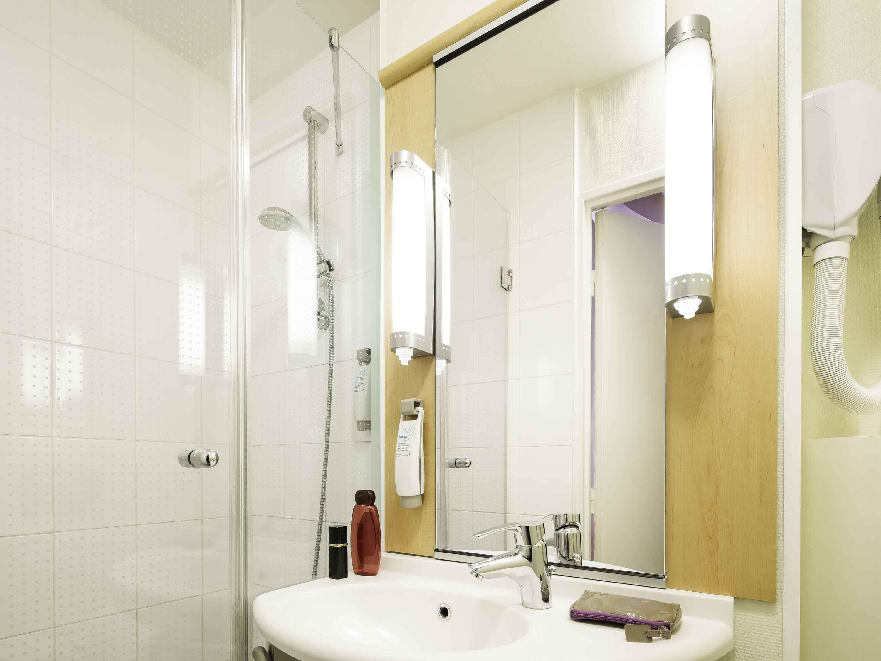 A modern bathroom with a glass shower enclosure, a white sink with a chrome faucet, and a large mirror.