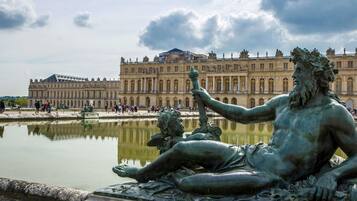 Un gran edificio de estilo clásico con una fuente reflectante en primer plano.