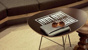 A round table with a black top and gold legs, a grey wallet, and a pair of sunglasses on top. - ibis Versailles Château (Versailles)