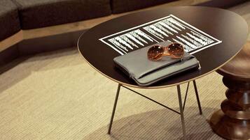 A round table with a black top and gold legs, a grey wallet, and a pair of sunglasses on top.