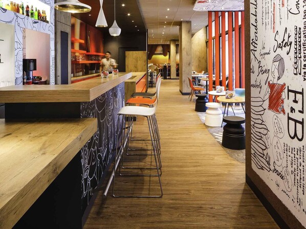 A modern bar area with wooden bar counters, metal stools, and a mix of seating options including chairs and tables. - ibis Versailles Château (Versailles)