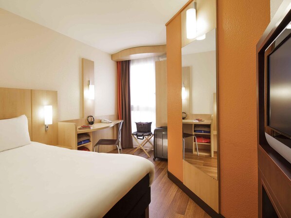 A hotel room with a bed, desk, chair, and TV. - ibis Versailles Château (Versailles)