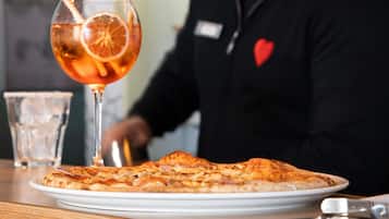 A pizza on a plate with a glass of orange juice and a straw.