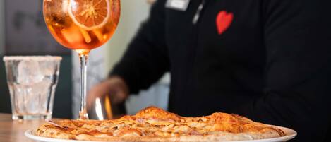 A pizza on a plate with a glass of orange juice and a straw.