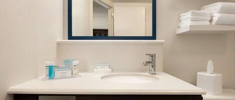 A bathroom with a white sink, a mirror, and a towel rack.
