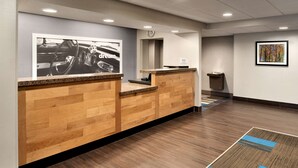 A reception area with a wooden reception desk, a clock on the wall, and a framed picture above the desk.