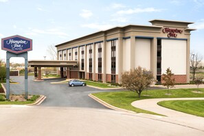 Um hotel Hampton Inn by Hilton com fachada moderna, estacionamento e entrada convidativa.