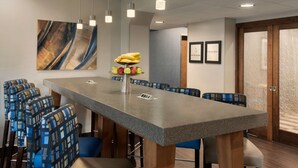A conference room with a long table, blue patterned chairs, and a fruit centerpiece.
