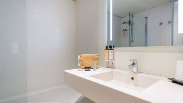 A modern bathroom with a large mirror, two sinks, and a glass shower enclosure.