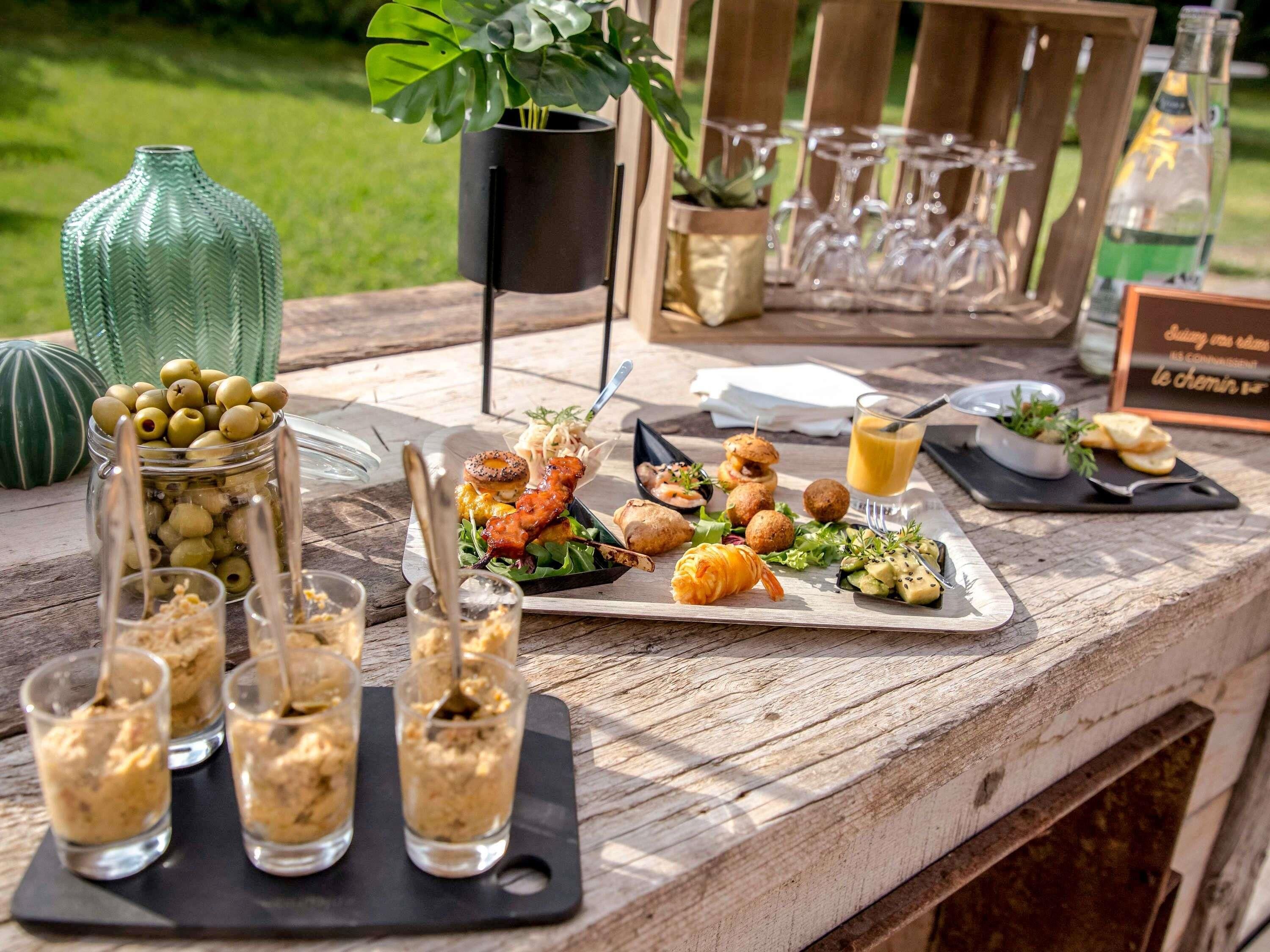 A wooden table with a variety of food items, including olives, a salad, and appetizers.