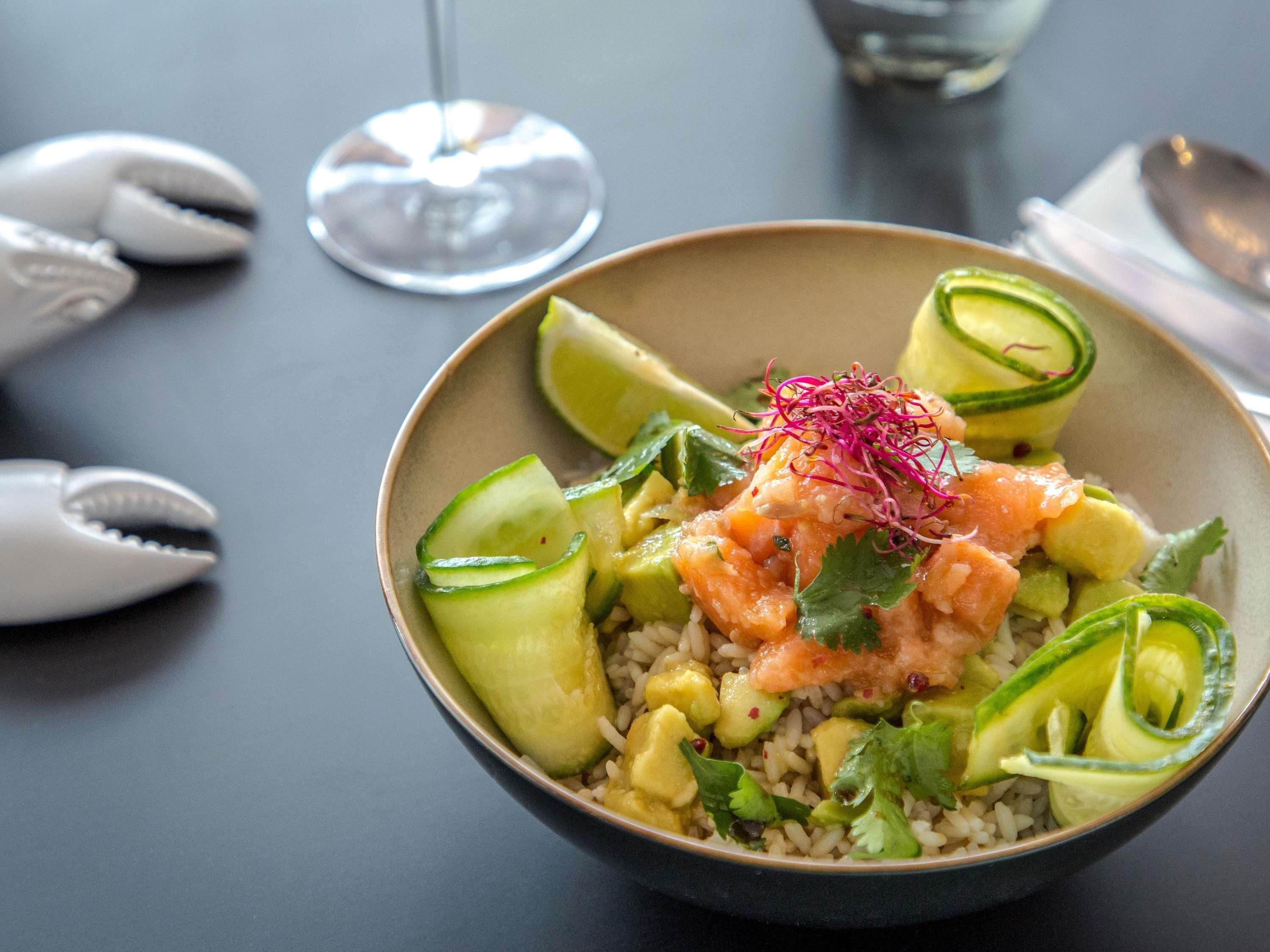 Eine Schüssel mit Essen, Reis, Avocado und Lachs, garniert mit Koriander und Mikrogrün.