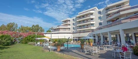 A modern hotel with a pool area, outdoor seating, and a well-maintained garden.