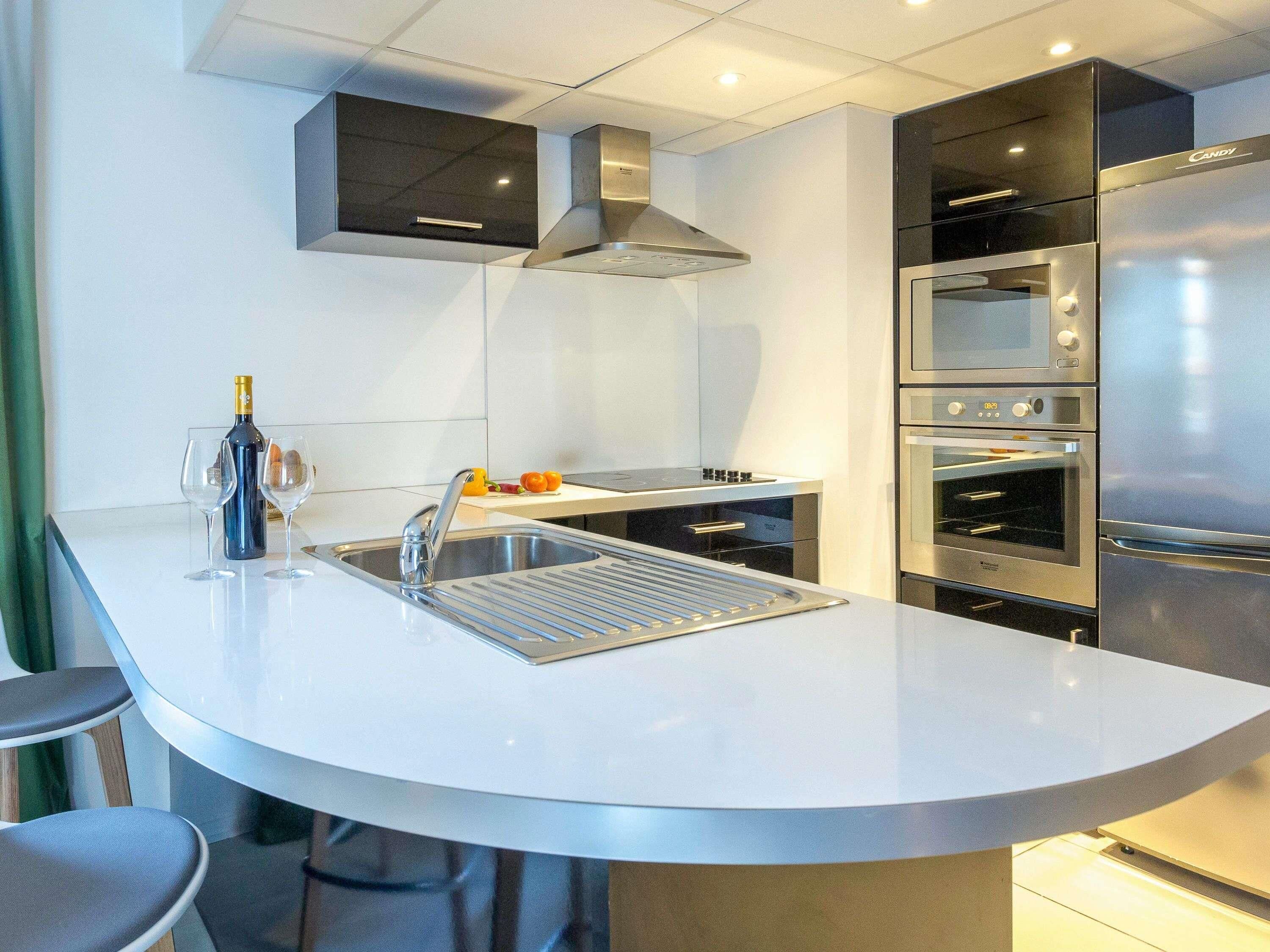 A modern kitchen with a central island, stainless steel appliances, and a built-in oven.