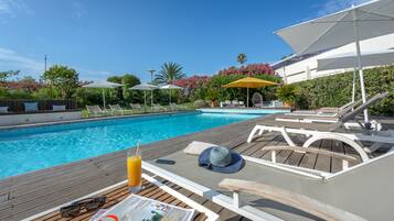 A poolside area with lounge chairs, umbrellas, and a wooden deck.