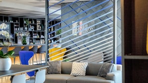 A modern hotel lobby with a bar area, seating, and a staircase.