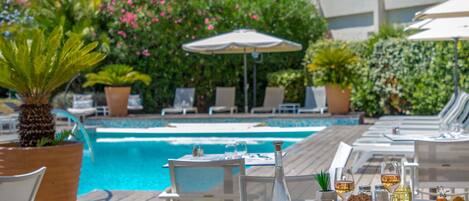 Un área de comedor junto a la piscina, con mesas y sillas.