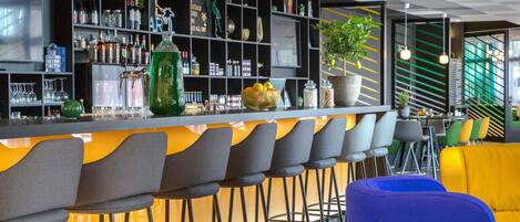 Zona de bar con techo a cuadros, estanterías con botellas y vasos, y taburetes.