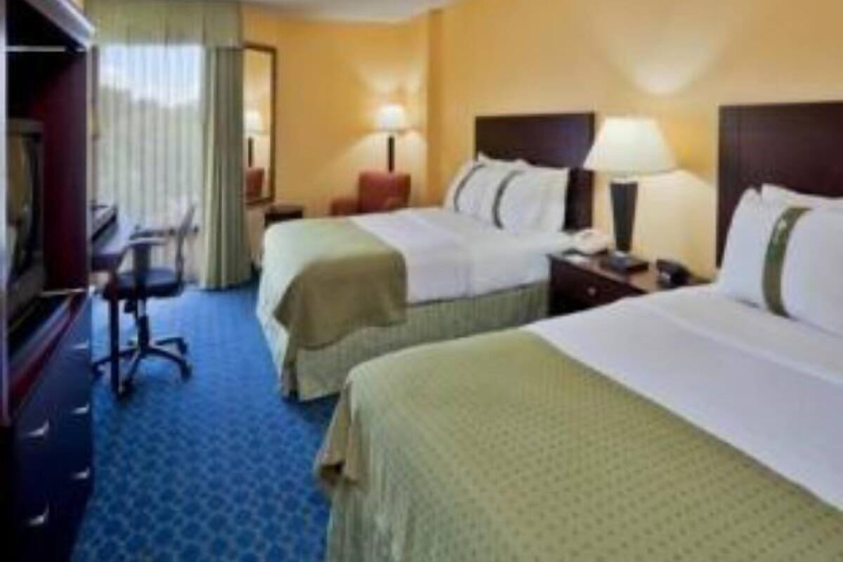 Een hotelkamer met twee bedden, een bureau, een stoel en een raam met gordijnen.