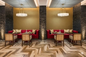 A dining area with red sofas, patterned walls, and a herringbone floor.